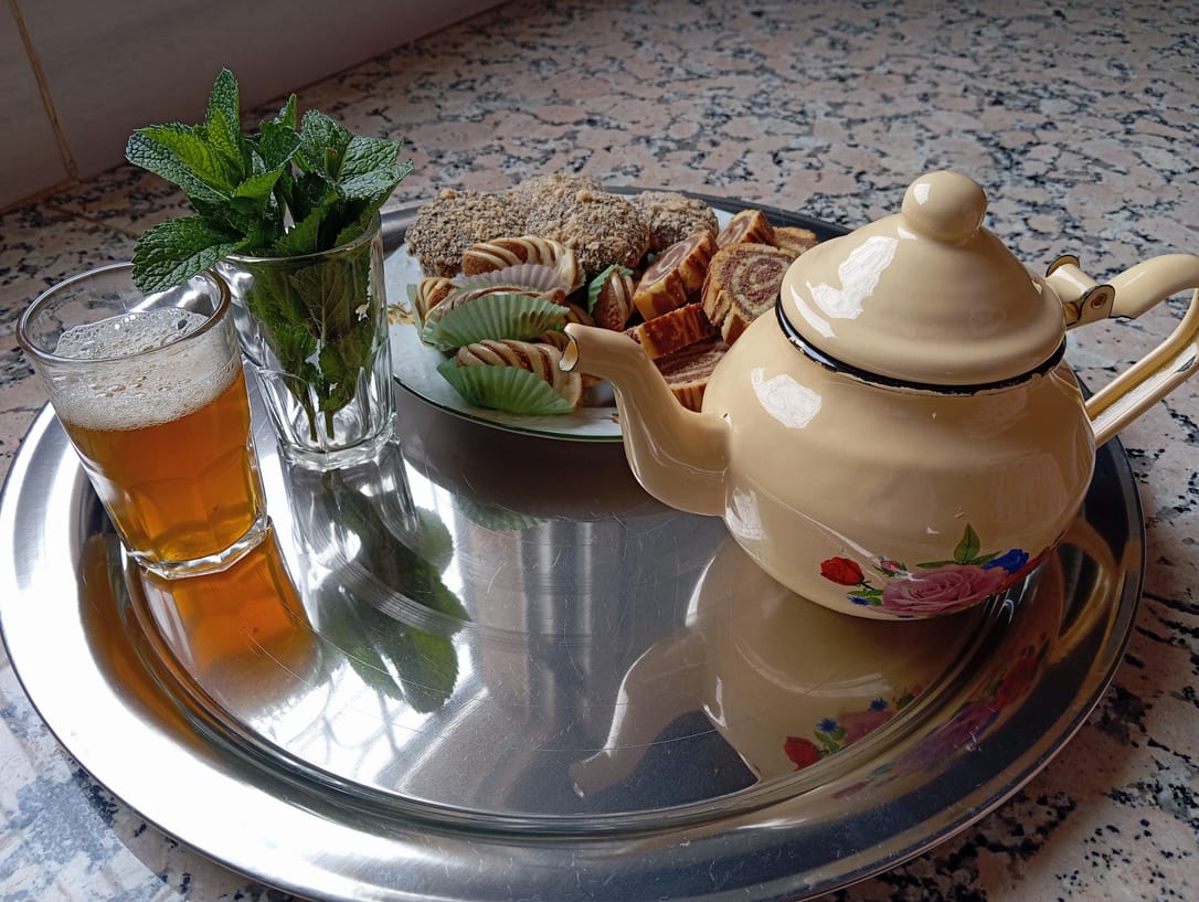 The teapot, a glass of mint and the sweets, on the tray